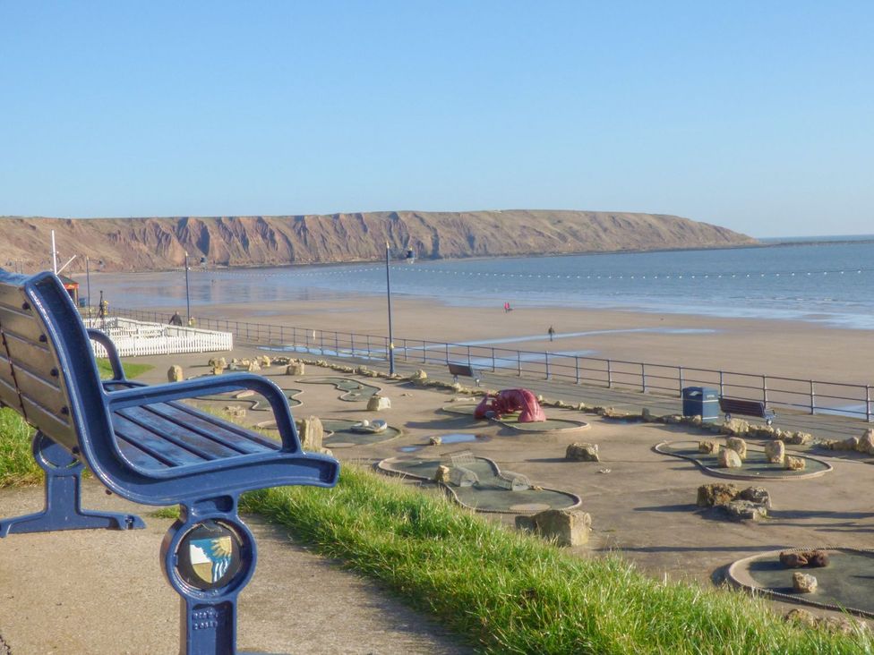 A beach scene with a bench and water at Chapel Cottage in Filey