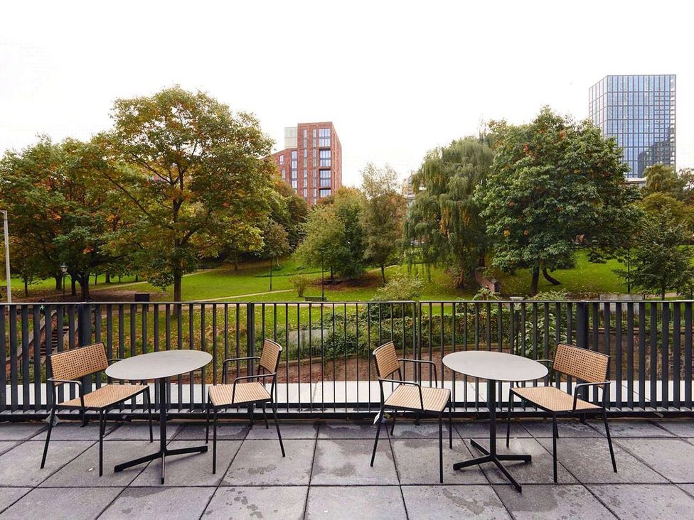 A terrace with tables and chairs overlooking a park at Central Apartment with Free Parking, Terrace and Gym in Manchester