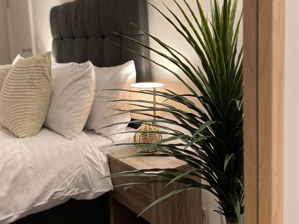 A bedroom with a bed, nightstand and lamp at Central Apartment with Free Parking, Terrace and Gym, Manchester