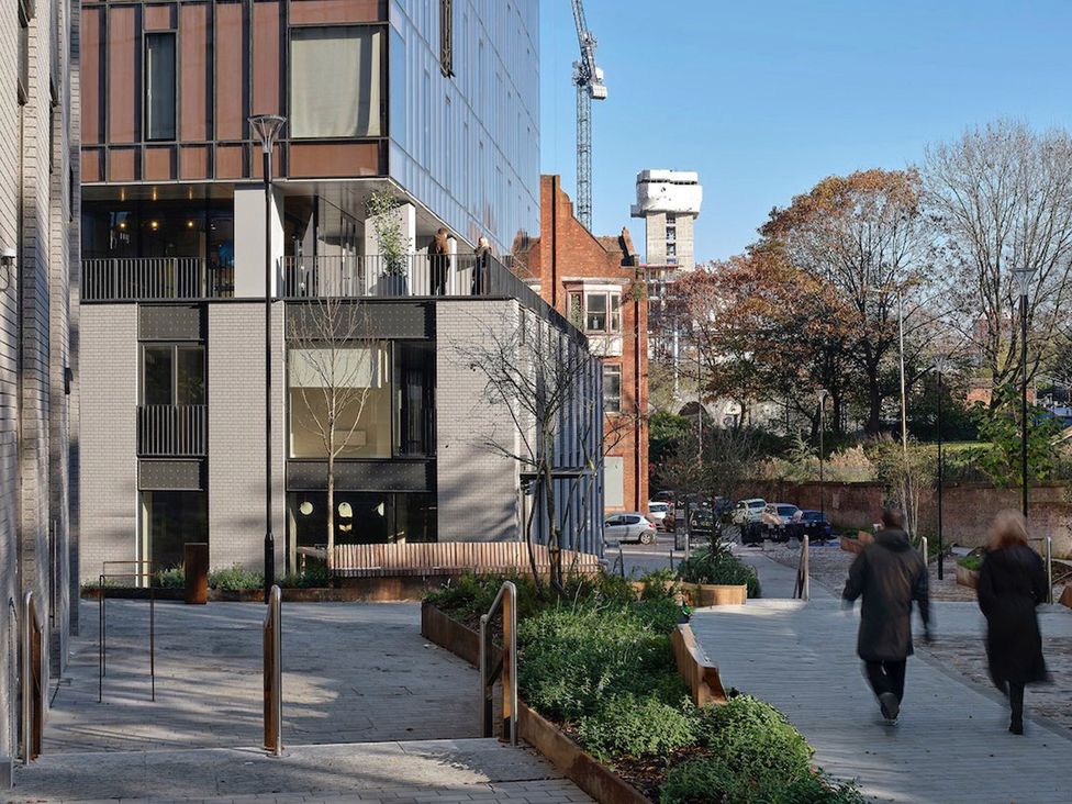 An outdoor view of a building with trees and people walking at Central Apartment with Free Parking, Terrace and Gym in Manchester