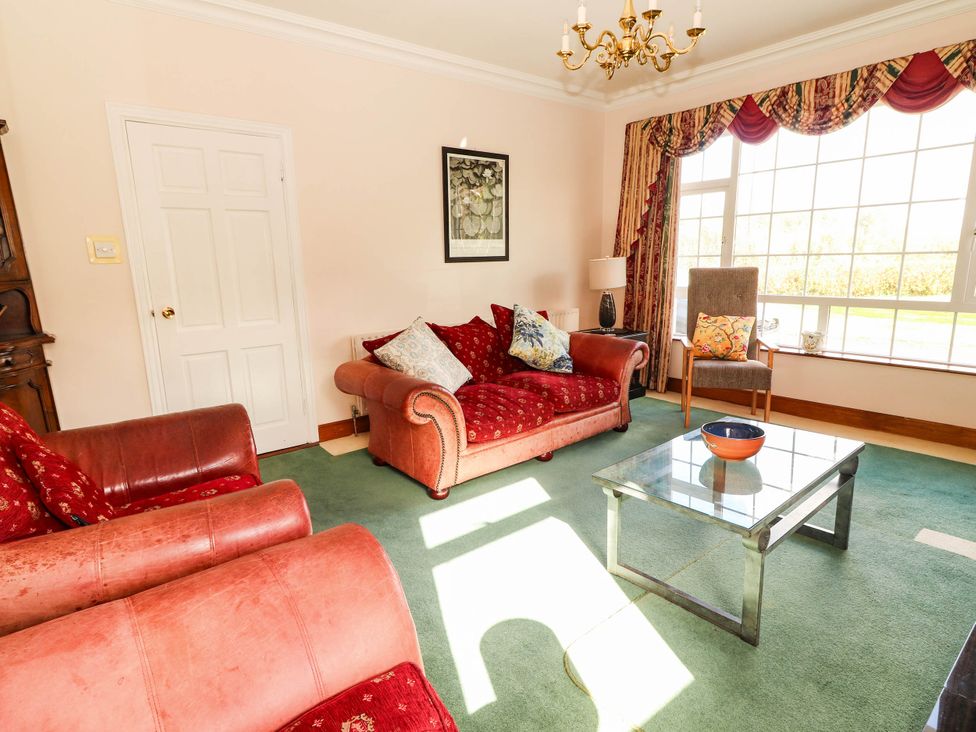 A living room with a sofa, chair, and coffee table at Cross Beg, Kilmihil, County Clare