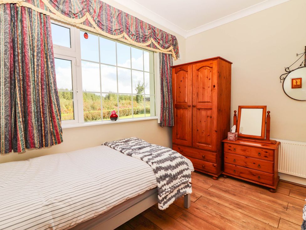 A bedroom with a bed and wardrobe at Cross Beg in Kilmihil, County Clare