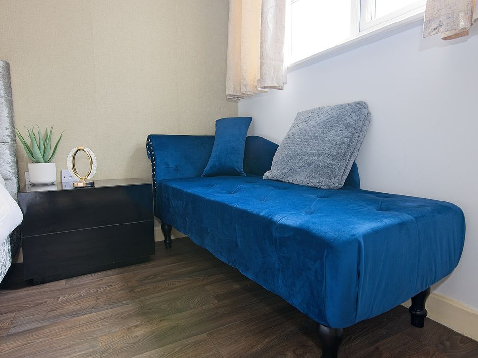 A blue chaise lounge with a pillow and end table in a bedroom at 2 Bedroom Apartment in Manchester