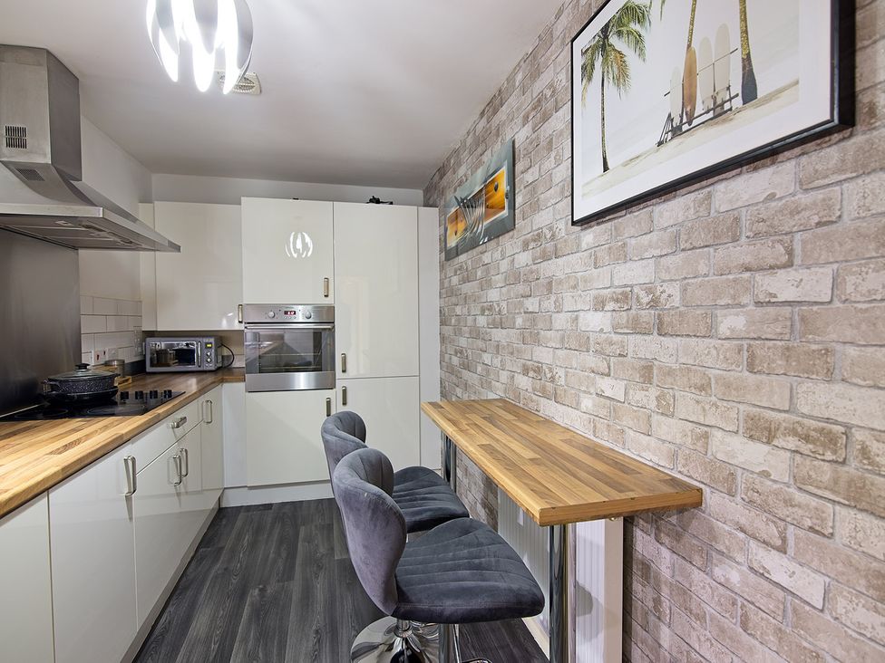 A kitchen with modern appliances and a bar stool at 2 Bedroom Apartment in Manchester