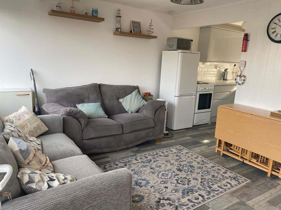 A living room with a sofa and kitchen appliances at Chalet 359 in Hemsby