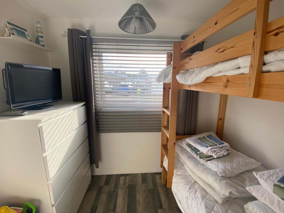 A bedroom with a bunk bed and television at Chalet 359 in Hemsby