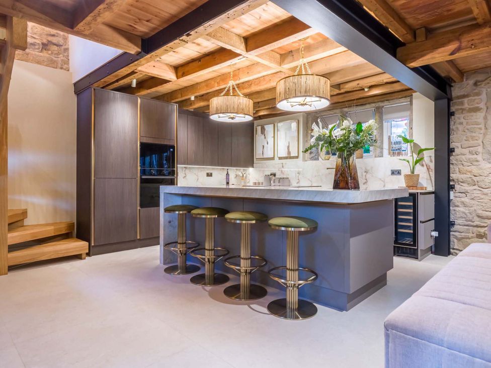 A kitchen with a bar island and stools at Heaven Lea Cottage