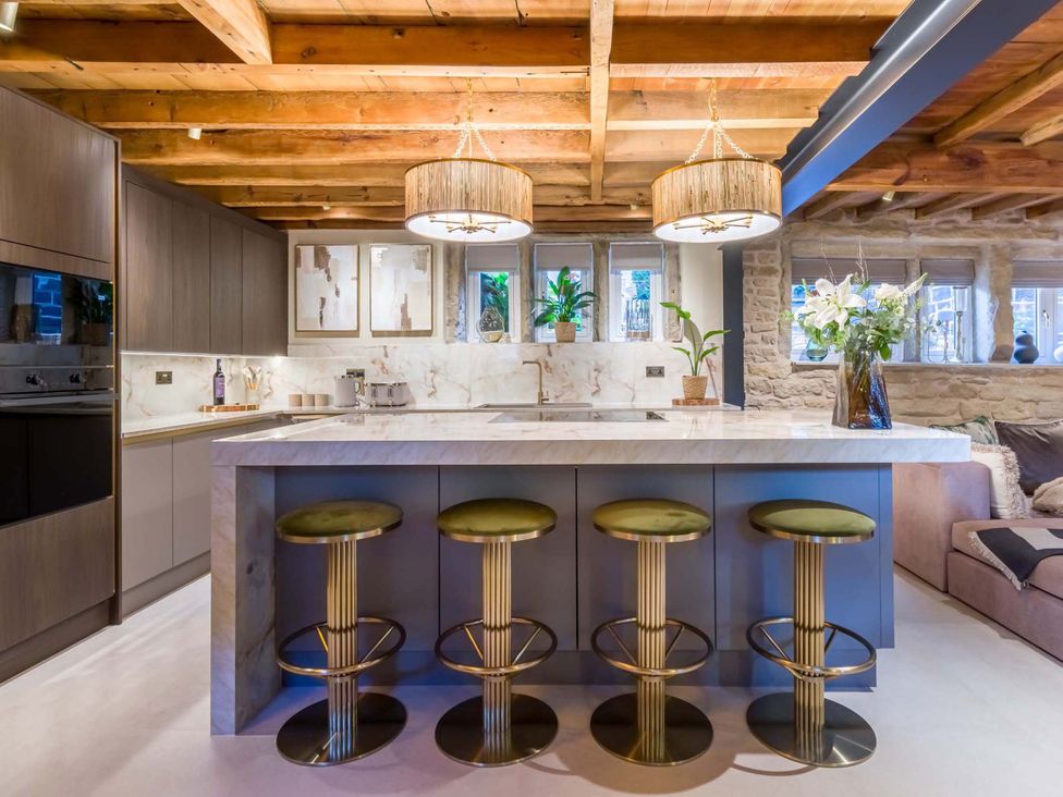 A kitchen with a marble island and stools at Heaven Lea Cottage
