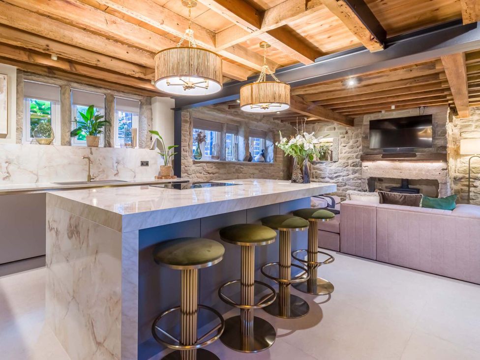 A kitchen with a marble island and bar stools at Heaven Lea Cottage