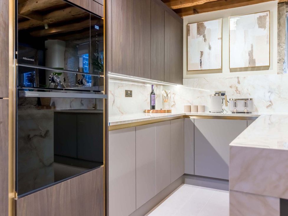 A kitchen with cabinets, appliances, and a countertop at Heaven Lea Cottage