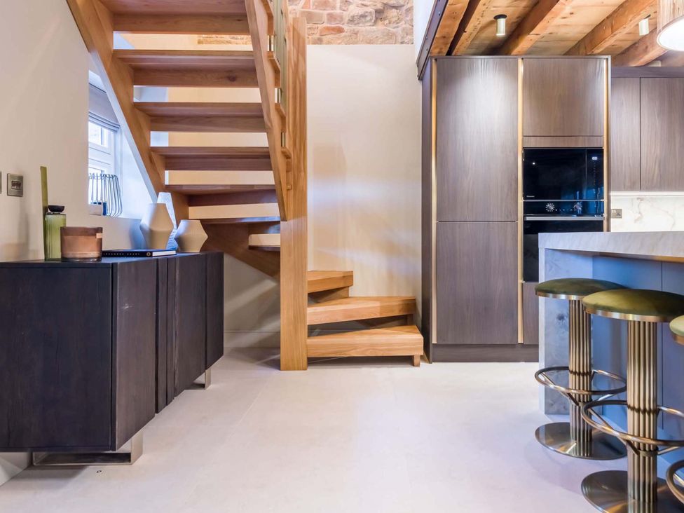 A kitchen with stairs and cabinets at Heaven Lea Cottage