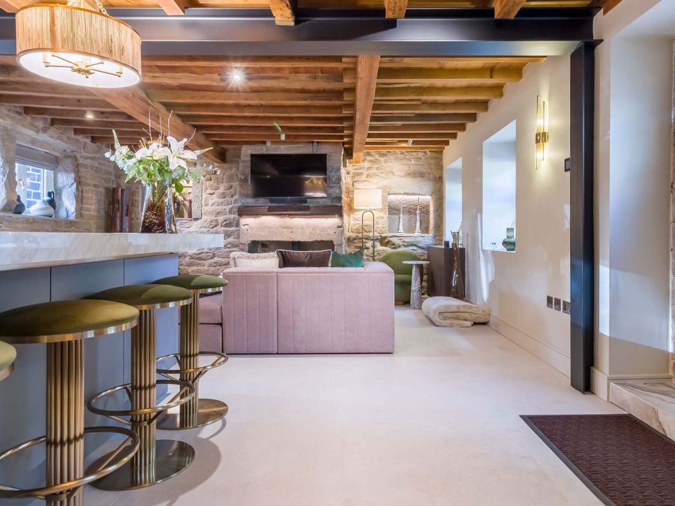 A living room with a sofa and bar stools at Heaven Lea Cottage