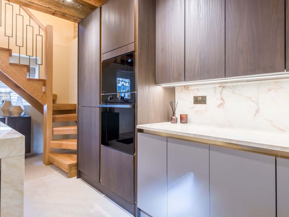 A kitchen with wooden staircase and cabinets at Heaven Lea Cottage