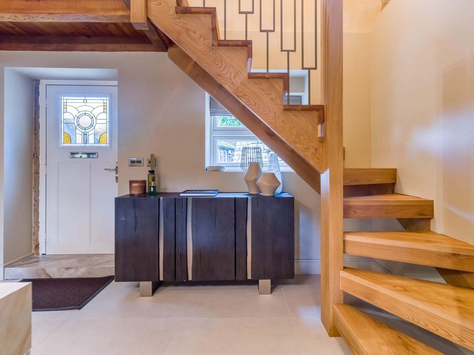 An entryway with a staircase and a side table at Heaven Lea Cottage