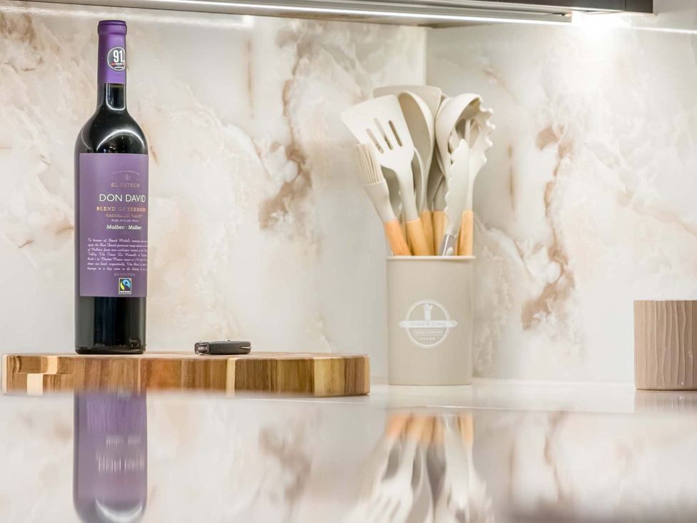 A wine bottle and kitchen utensils on a counter at Heaven Lea Cottage 