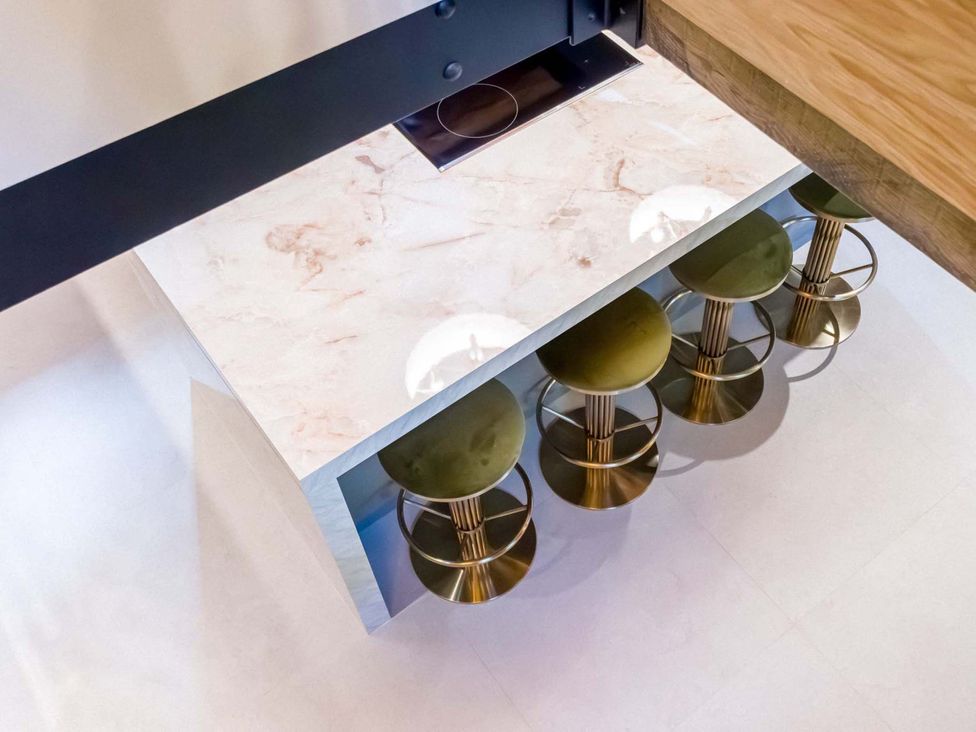 A kitchen island with bar stools and a cooktop at Heaven Lea Cottage 