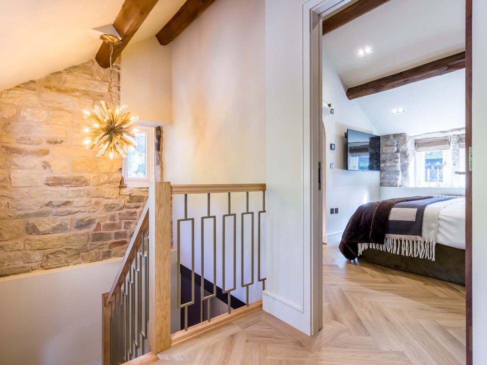 A hallway with stairs and a door to a bedroom at Heaven Lea Cottage 