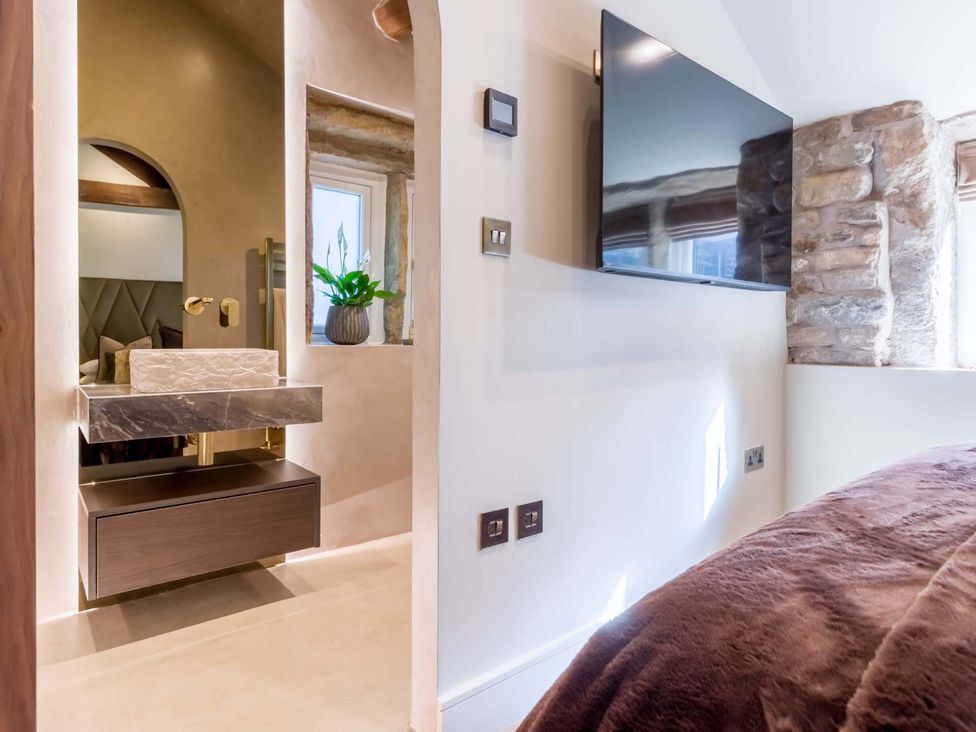 A bathroom featuring a sink, mirror, and television at Heaven Lea Cottage
