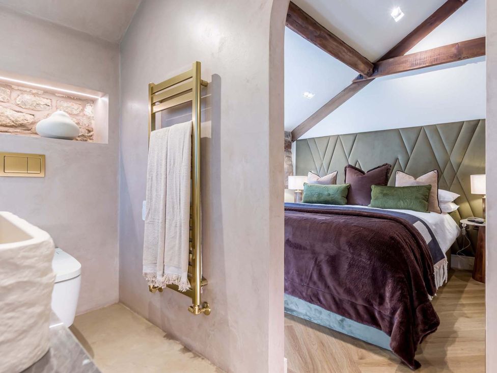 A bathroom with a toilet and towel radiator leading to a bedroom at Heaven Lea Cottage