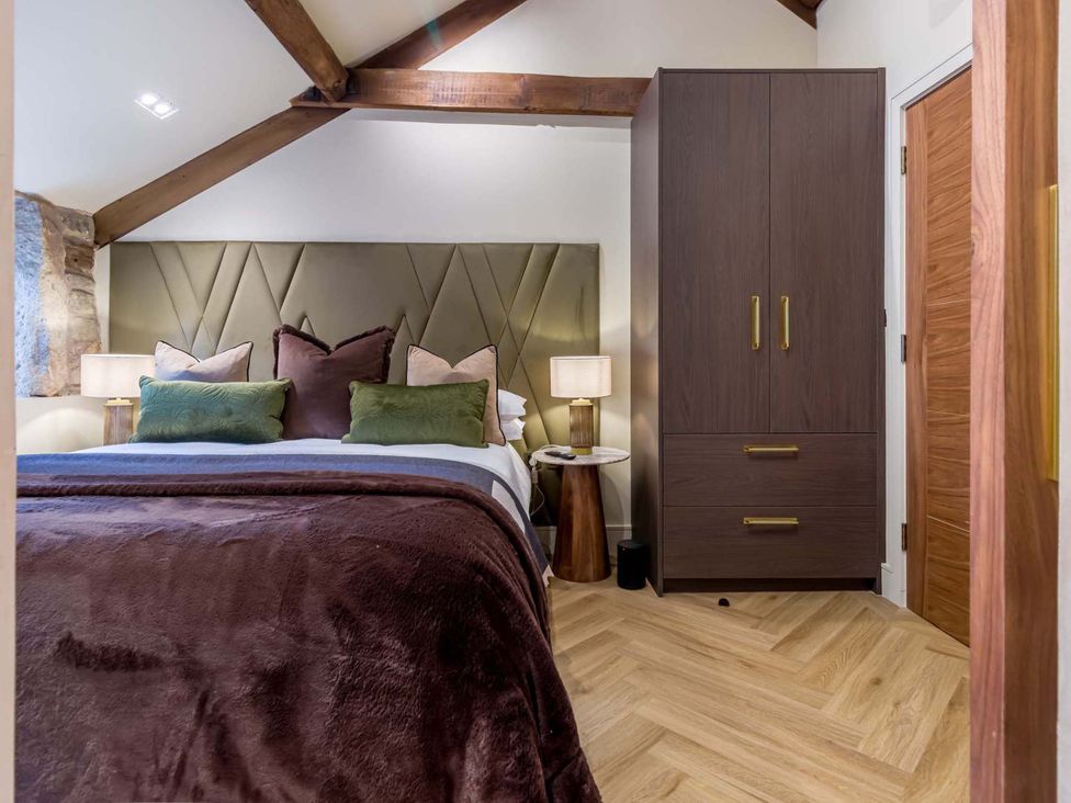 A bedroom with a bed, nightstand, and wardrobe at Heaven Lea Cottage