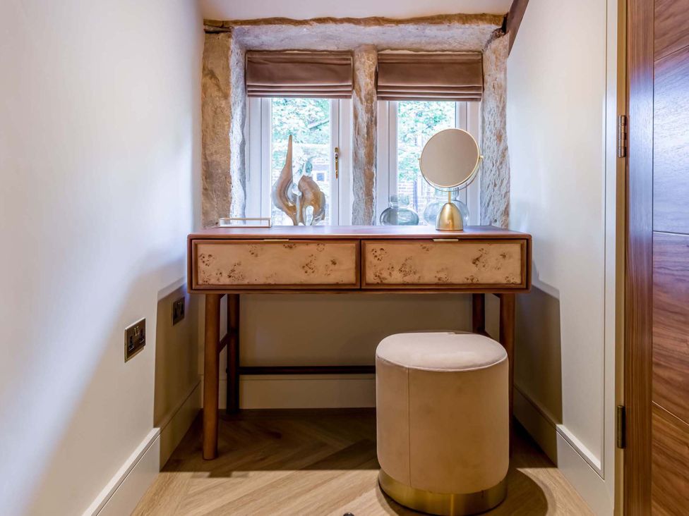 A dressing area with a vanity table and mirror at Heaven Lea Cottage