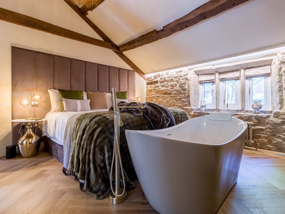 A bedroom featuring a bed and a bathtub at Heaven Lea Cottage