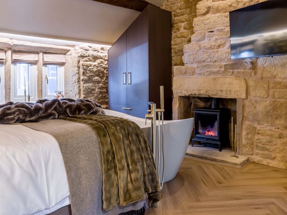 A bathroom with a bathtub and a fireplace at Heaven Lea Cottage