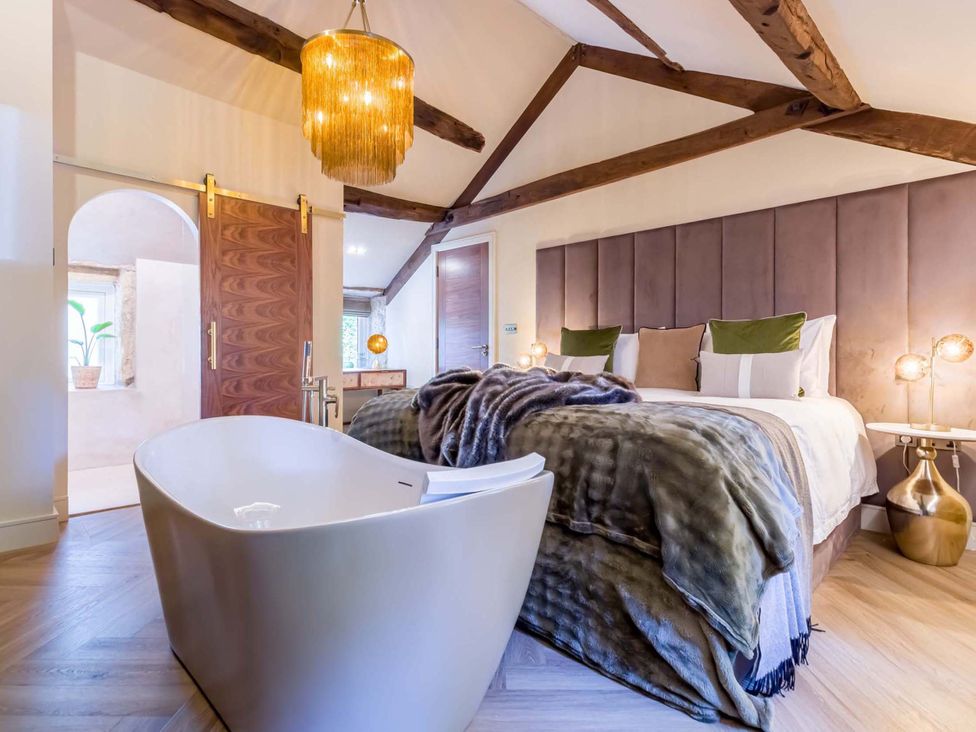A bedroom with a bed and a bathtub at Heaven Lea Cottage