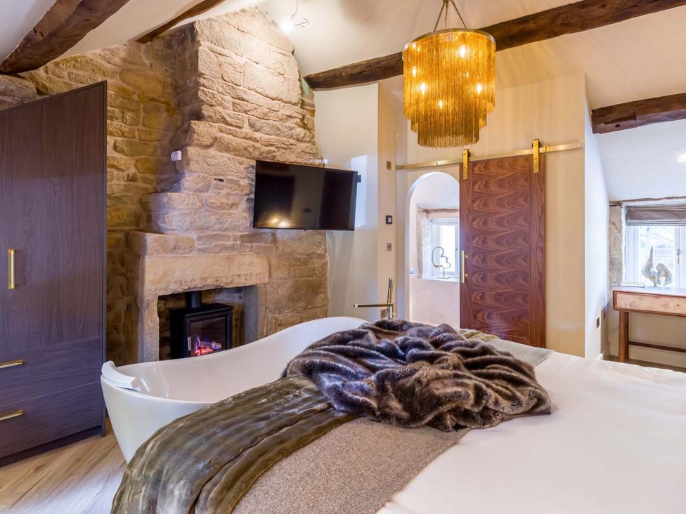 A bedroom with a bathtub and a television at Heaven Lea Cottage