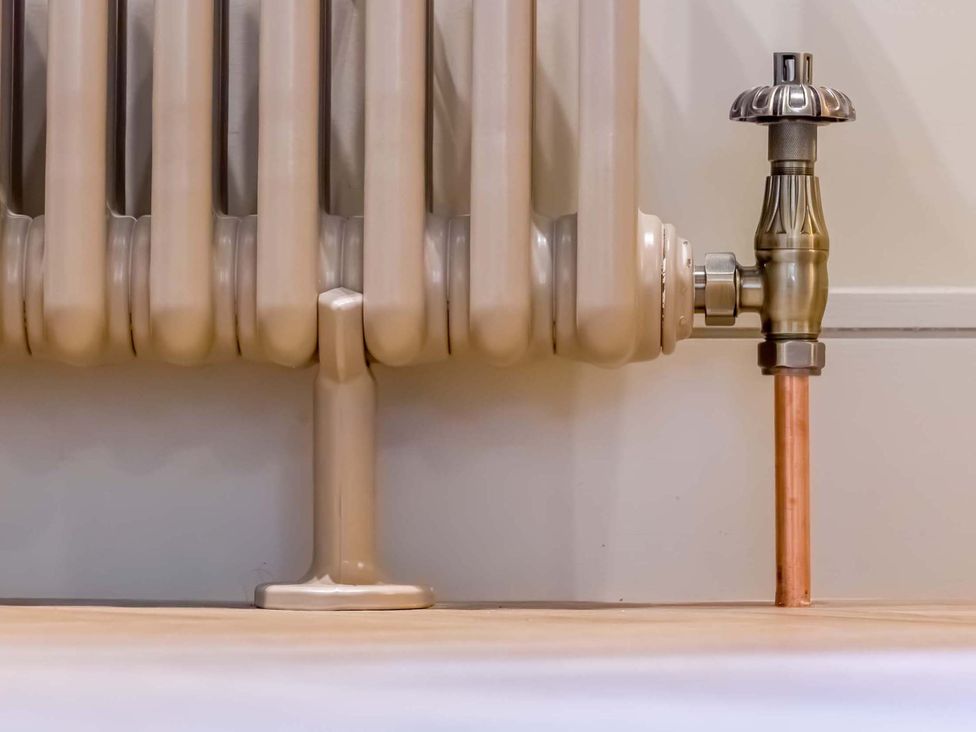 A radiator with a valve and copper pipe at Heaven Lea Cottage