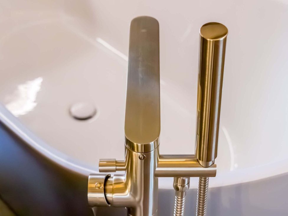 A faucet and shower handle in a bathtub at Heaven Lea Cottage