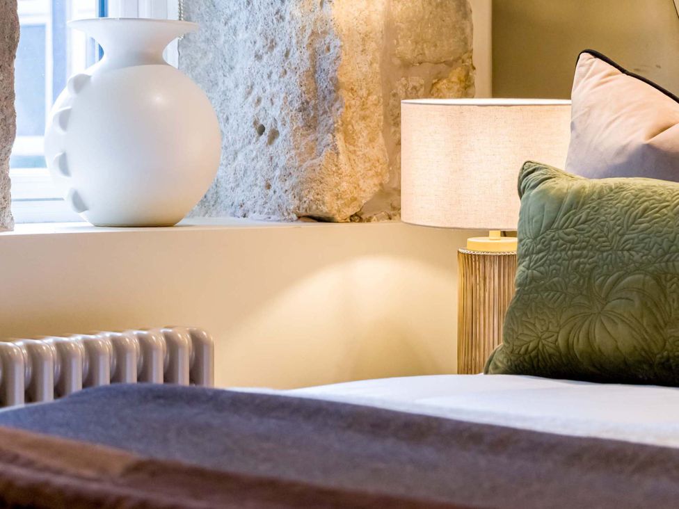 A bedroom with a vase, lamp, and bed at Heaven Lea Cottage