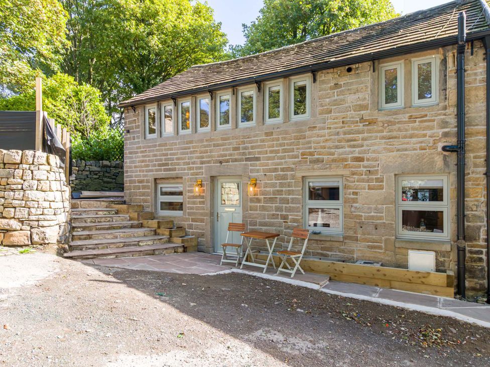 An outdoor area with a stone wall, stairs, and seating at Heaven Lea Cottage