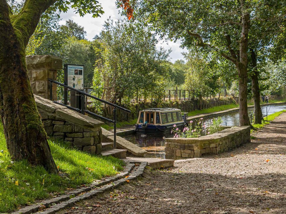 A pathway beside a canal with a boat and trees at Heaven Lea Cottage