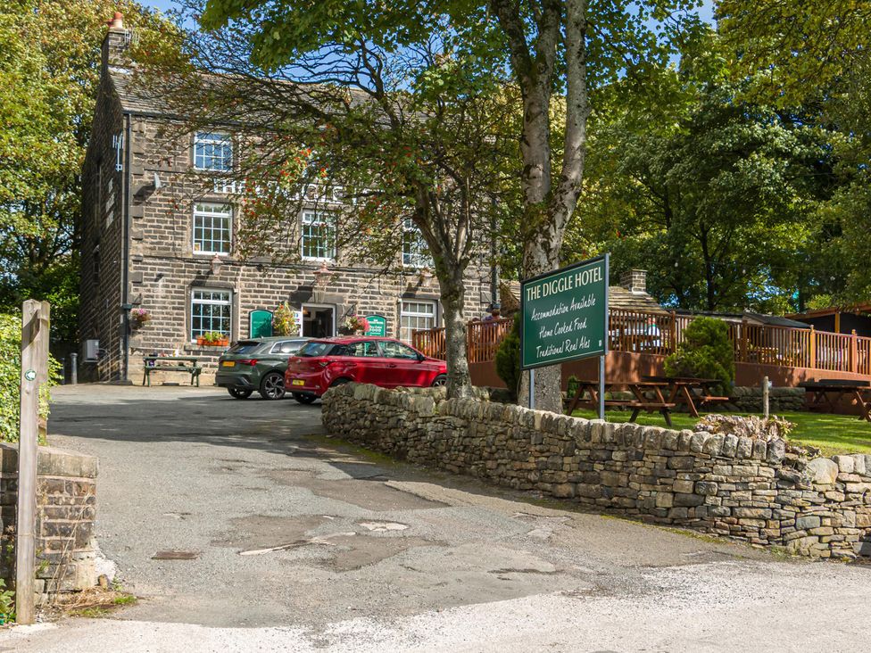An exterior view of The Diggle Hotel with parking area at Heaven Lea Cottage