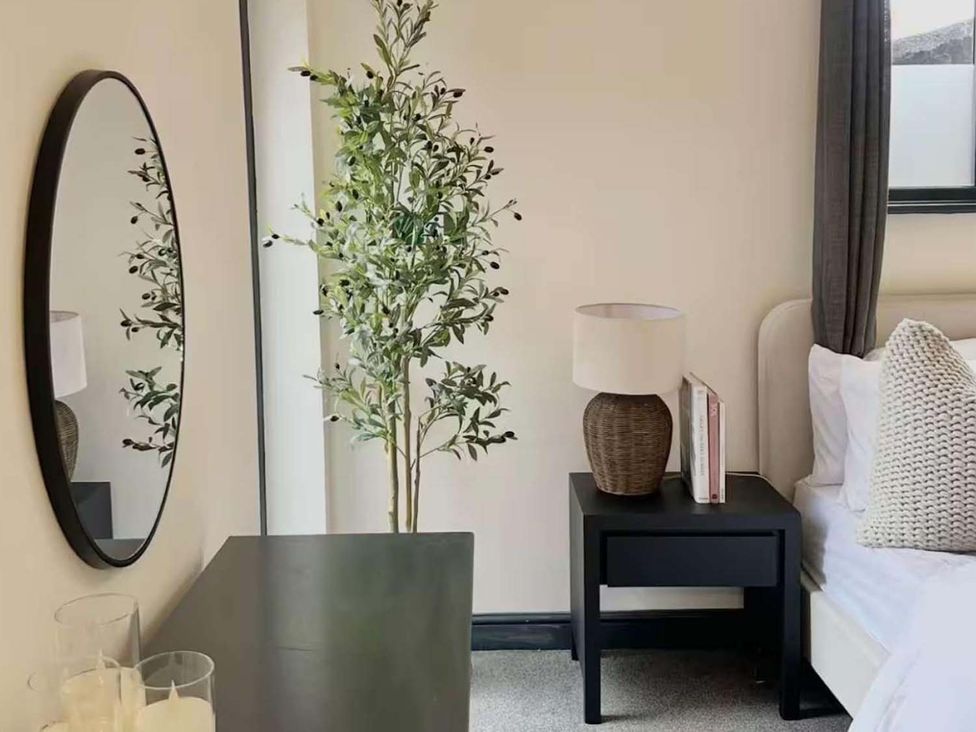 A bedroom with a mirror and bedside table at New Cosy Retreat in Matlock Bath