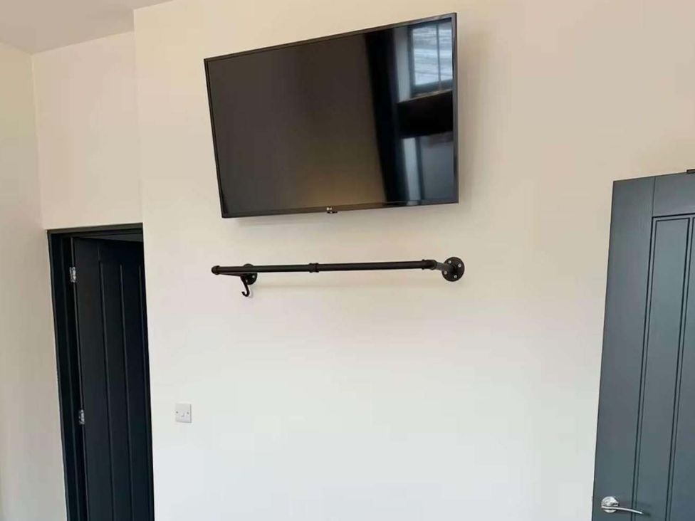 A wall with a television mounted and a hook at New Cosy Retreat in Matlock Bath