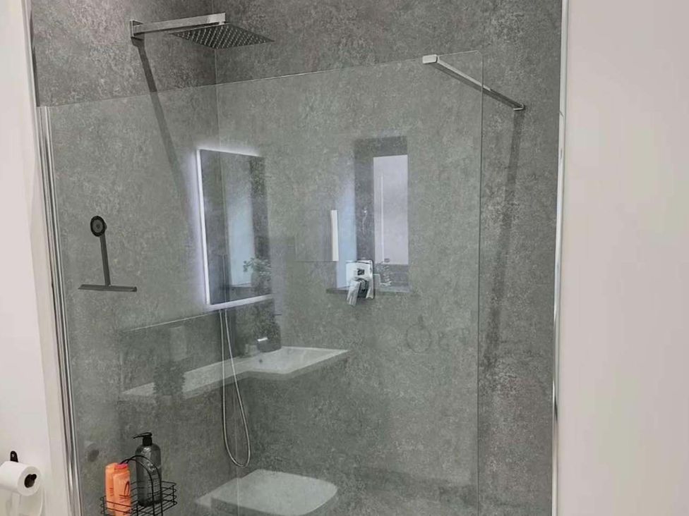 A shower area with a glass panel and a sink at New Cosy Retreat in Matlock Bath