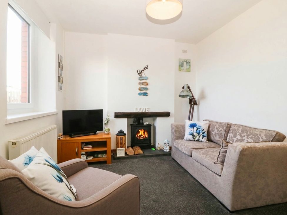A living room with a sofa and television at Derwen-Las in Penmaenmawr
