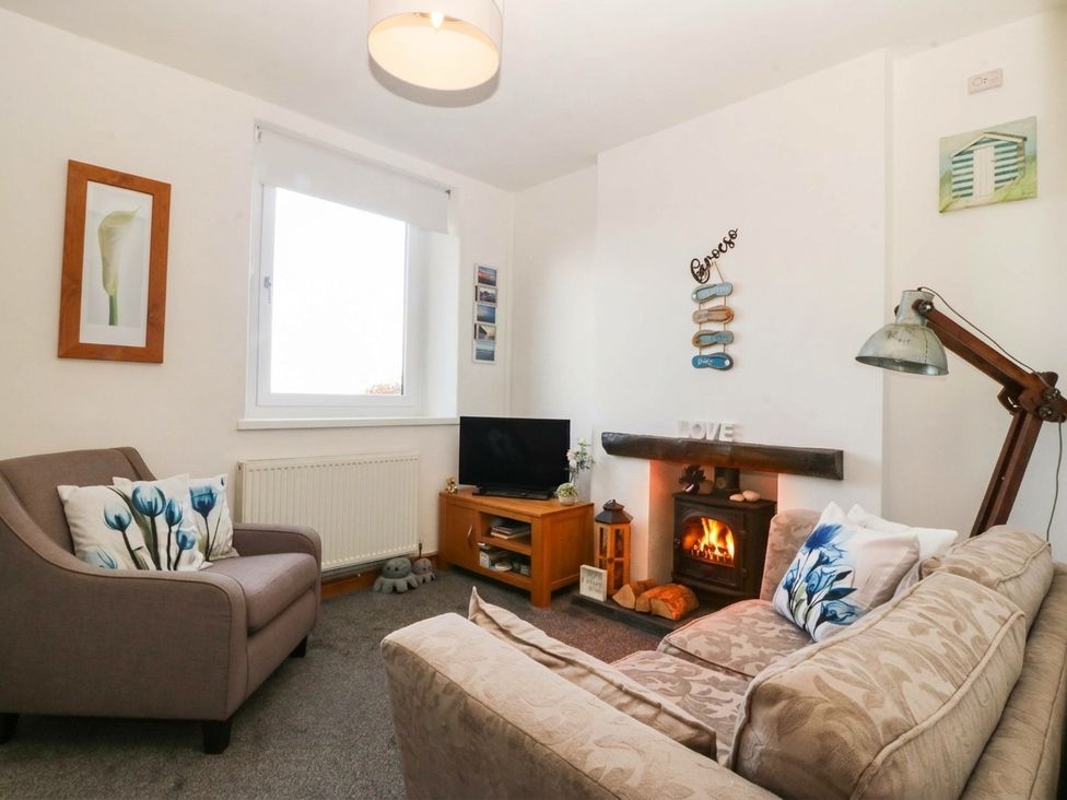 A living room with a sofa and television at Derwen-Las in Penmaenmawr