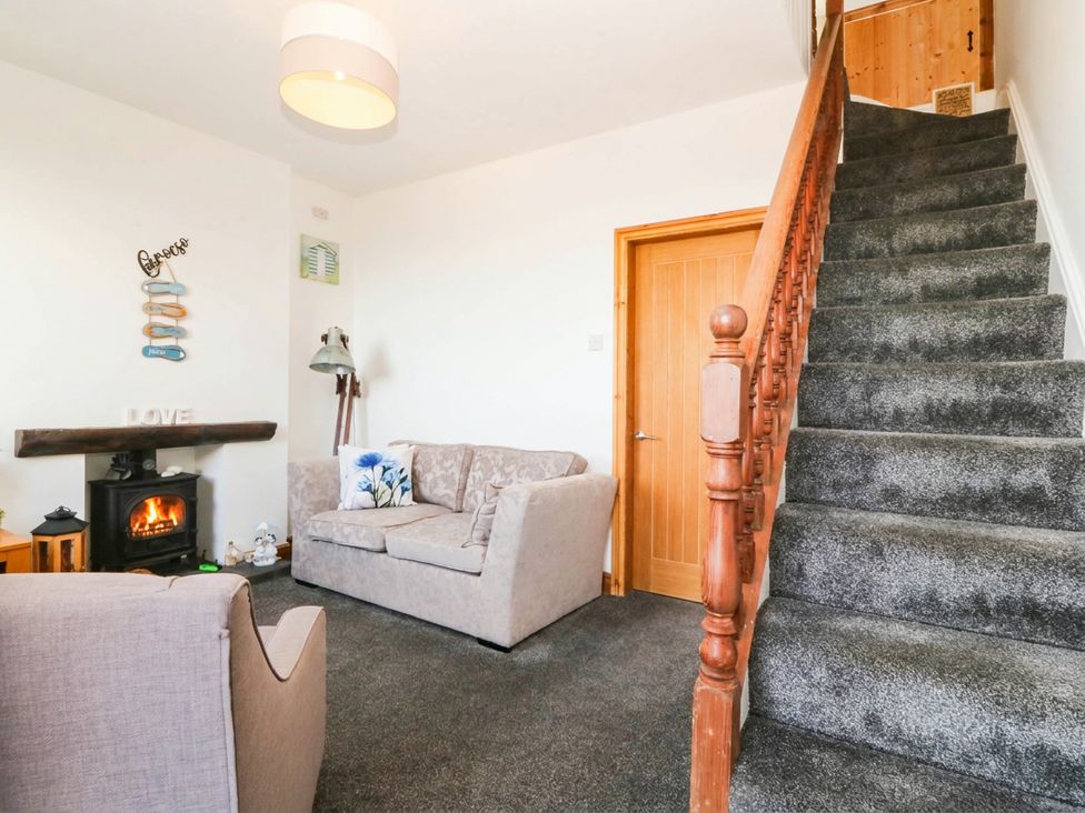 A living room with a sofa and fireplace at Derwen-Las in Penmaenmawr