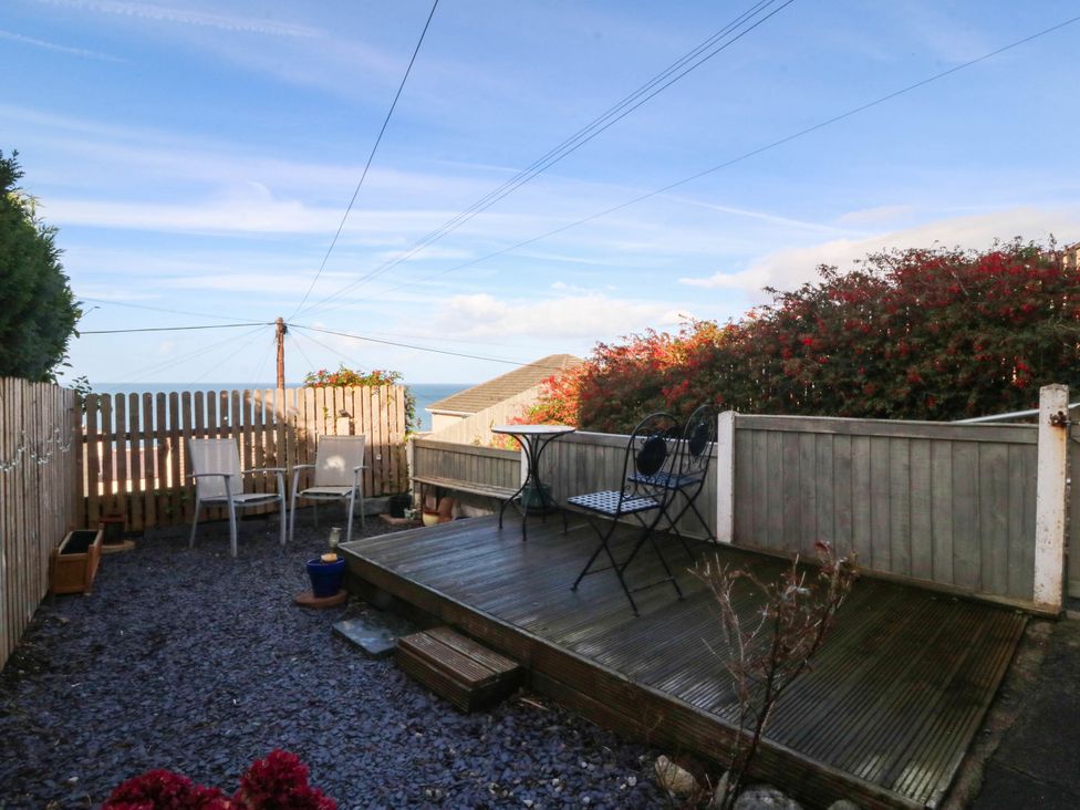 A garden with a wooden deck and outdoor chairs at Derwen-Las in Penmaenmawr