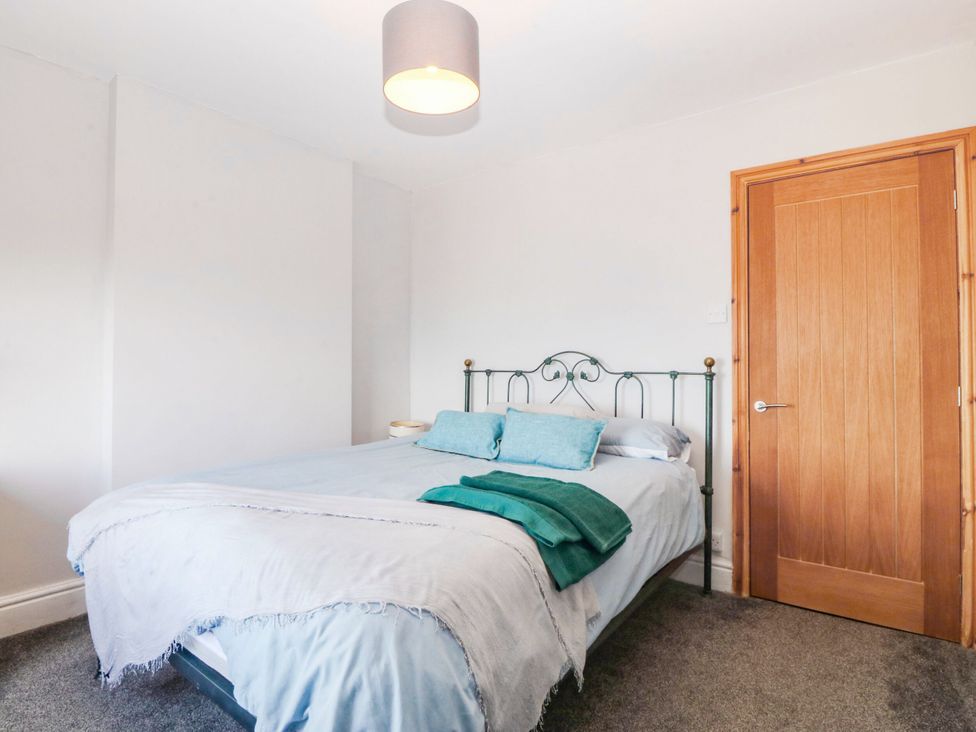 A bedroom with a bed and a door at Derwen-Las in Penmaenmawr