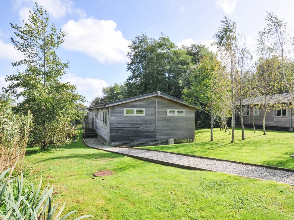 A cabin surrounded by grass and trees at 22 Meadow Retreat in Dobwalls