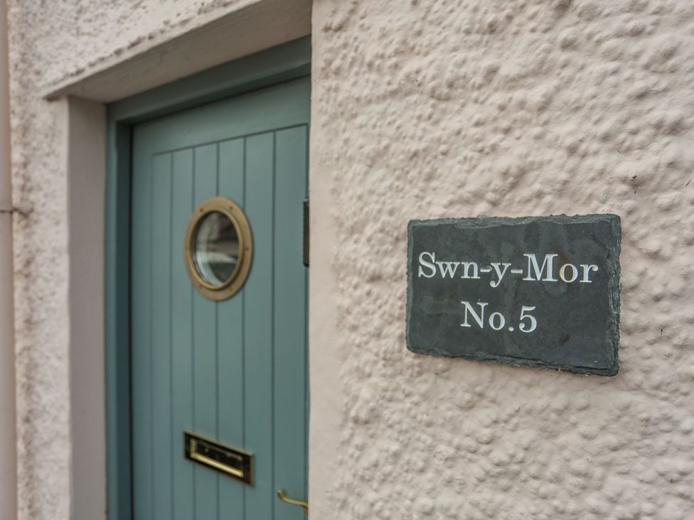 A door with a circular window and sign reading Swn-y-Mor No. 5 at Swn y Mor (Wexham) Beaumaris