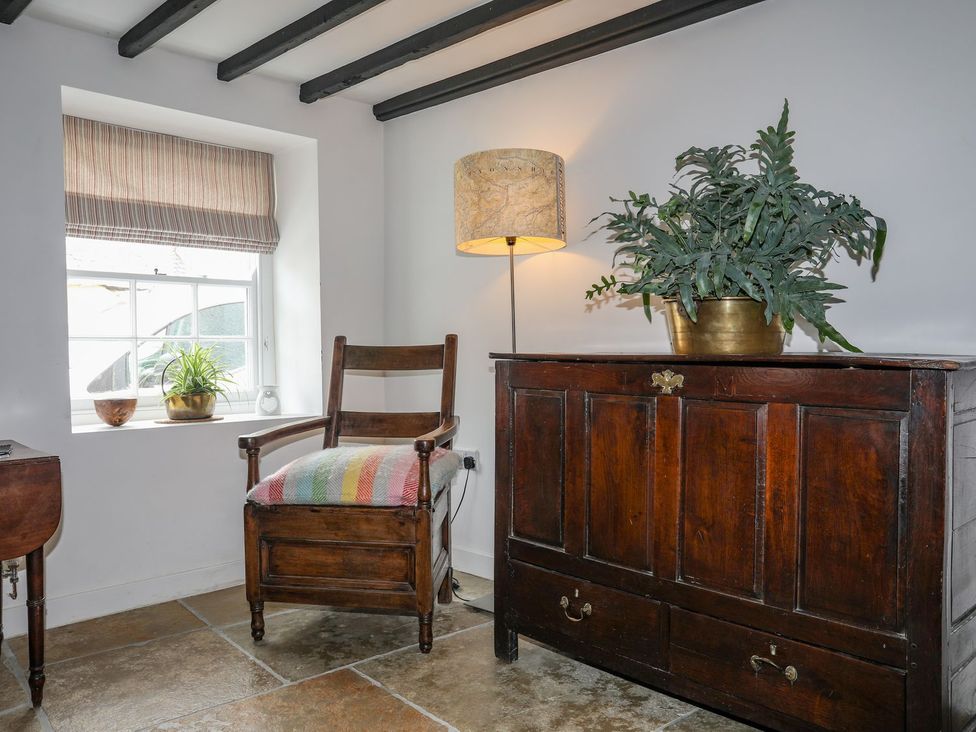 A room with a chair, a lamp, a plant, and a chest at Swn y Mor (Wexham) Beaumaris