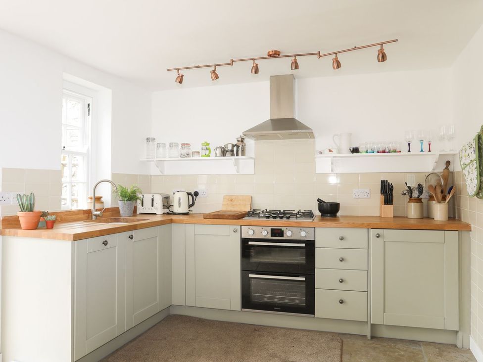 A kitchen with cabinets, stove, and sink at Swn y Mor (Wexham) Beaumaris