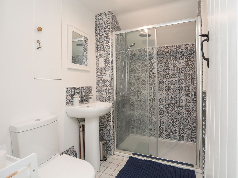 A bathroom with a shower, sink, and toilet at Swn y Mor (Wexham) Beaumaris