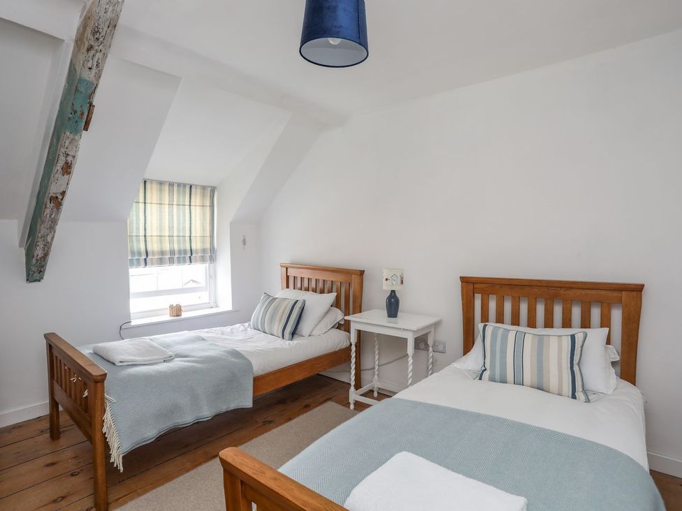 A bedroom with two single beds and a bedside table at Swn y Mor (Wexham) Beaumaris