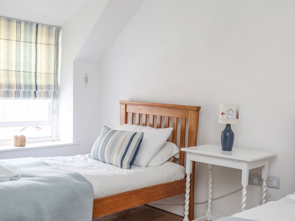 A bedroom with two beds and a bedside table at Swn y Mor (Wexham) Beaumaris